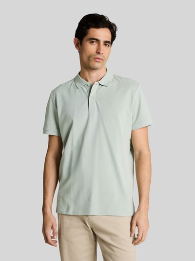 Männermodel trägt Regular Fit Poloshirt aus reiner Baumwolle von Tom Tailor in Optik: Unifarben mit Logo-Stitching, Piqué-Struktur, Nahaufnahme Oberkörper.