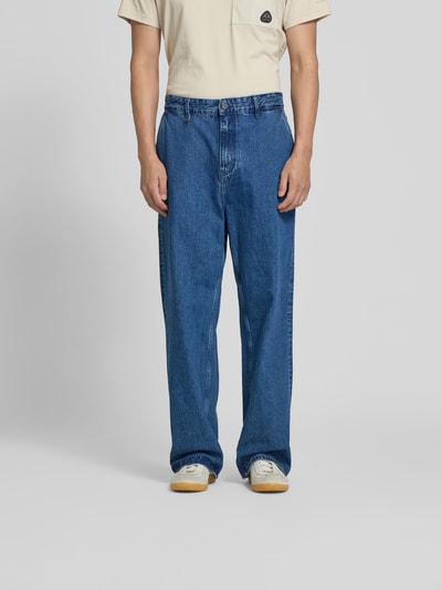 Männermodel trägt Straight Fit Jeans mit Logo-Detail von WON HUNDRED aus Reiner Baumwolle, blaue Farbe, Eingriff- und Gesäßtaschen, Knopf- und Reißverschluss, Ganzkörperansicht von vorne.