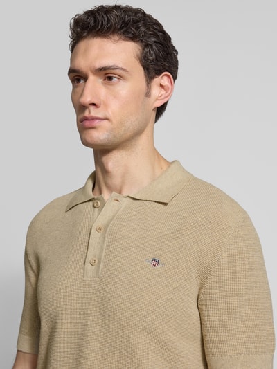 Männermodel trägt Regular Fit Poloshirt mit Label-Stitching von Gant aus reiner Baumwolle in Beige, Nahaufnahme Oberkörper.