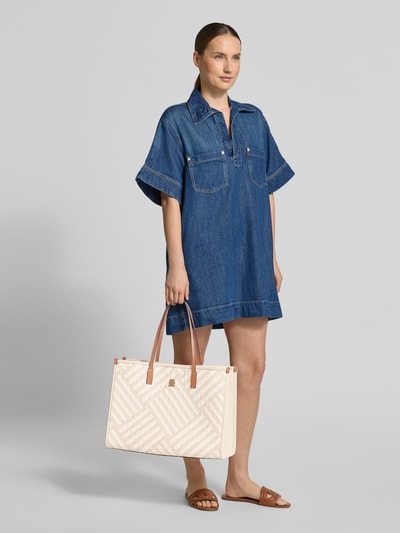Frauenmodel trägt Henkeltasche mit Webmuster von Tommy Hilfiger in Bi-Color Optik, Magnetverschluss, Logo-Applikation, gewebt, Ganzkörperansicht von vorne.