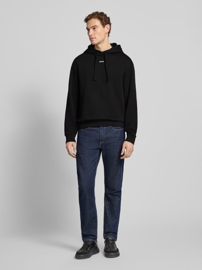 Männermodel trägt Regular Fit Hoodie aus reiner Baumwolle Modell 'DAPO' von HUGO in Schwarz, schlichte Optik, Ganzkörperansicht von vorne.