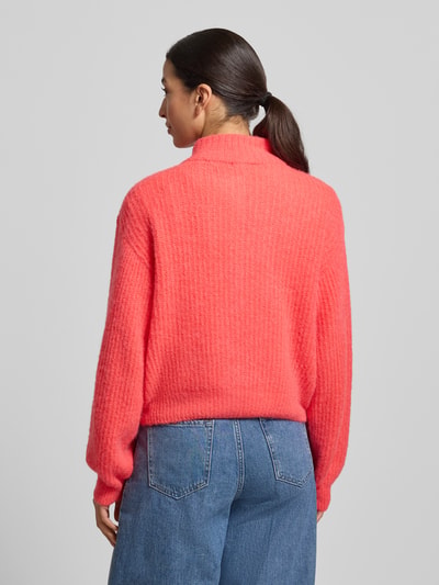 Frauenmodel trägt Strickjacke mit Knopfleiste von American Vintage, leuchtend rosa, lockerer Schnitt, Material-Mix, Ganzkörperansicht Rückansicht.