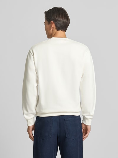 Männermodel trägt Regular Fit Sweatshirt aus Baumwoll-Mix von Lacoste in Weiß, kombiniert mit blauer Hose, Ganzkörperansicht Rückansicht. Herren Sweatshirt von Lacoste.
