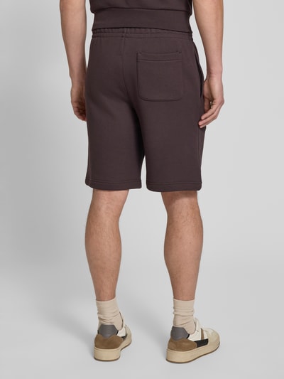 Männermodel trägt Relaxed Fit Sweatshorts aus reiner Baumwolle von Lacoste, Optik: Unifarben, Logo-Detail, Ganzkörperansicht Rückansicht.