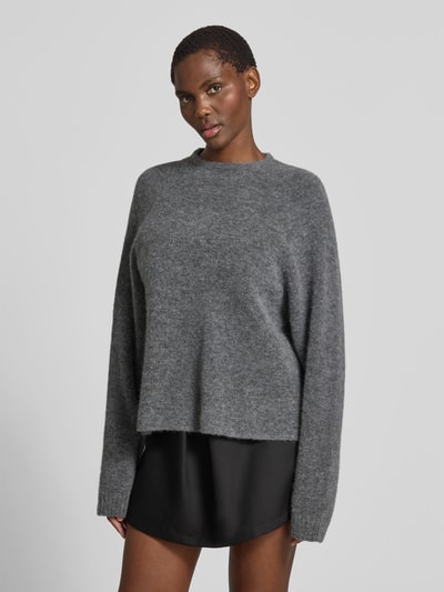 Frauenmodel trägt Pullover in Strick-Optik aus Alpaka-Mix von black palms in Grau, Relaxed-Fit, mit Rundhalsausschnitt, elastischen Ärmelabschlüssen, Rückenlänge bei Größe S 62 cm, Nahaufnahme Oberkörper.