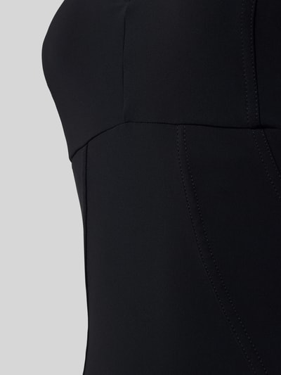 Frauenmodel trägt Badeanzug mit Shaping-Effekt und V-Ausschnitt Modell 'Vertigo' von Arena, Material mit patentiertem Sensitive® Fabrics, Shapewear, Logo-Print, verstellbare Träger, höchster Tragekomfort, chlorbeständig, UV-Schutz, schnelltrocknend, Detailaufnahme.