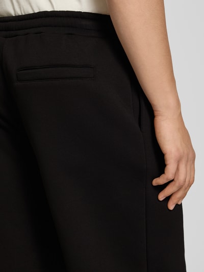Männermodel trägt Sweatpants mit Logo-Print und Gesäßtasche von REVIEW, Schwarz, Baumwoll-Mix, Eingrifftaschen, Gerader-Schnitt, Detailaufnahme.