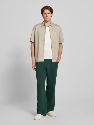 Männermodel trägt Regular Fit Sweatpants mit Gesäßtasche von REVIEW in Dunkelgrün, Baumwoll-Mix, elastischer Bund, Ganzkörperansicht von vorne.