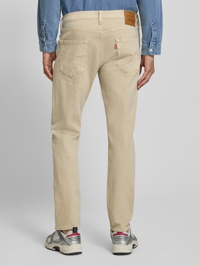 Męski model nosi beżowe jeansy o kroju tapered fit z bawełnianej mieszanki Tapered Fit Jeans aus Baumwoll-Mix Modell '502™ TAPER' od Levi's®, widok całej sylwetki z tyłu, Herren Tapered Fit Jeans von Levi's®.