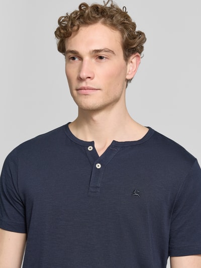 Männermodel trägt T-Shirt mit kurzer Knopfleiste von Lerros in Dunkelblau, Reine Baumwolle, Gerader-Schnitt, Logo-Stitching, Nahaufnahme Oberkörper.