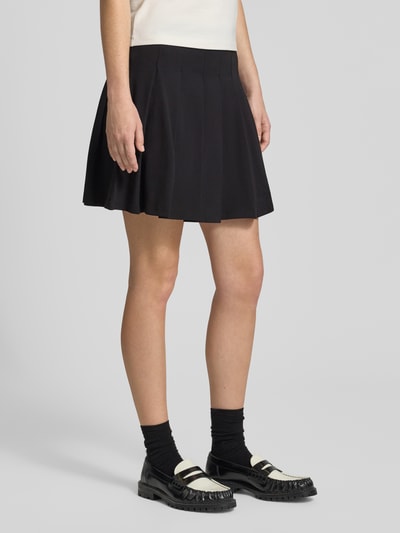 Kobiece model nosi spódnicę mini z mieszanki bawełny Ausgestellter Mini-Rock aus Baumwoll-Mix Modell 'Nalham_B' od Hugo Blue, czarny kolor, gładka faktura, długość mini, Ganzkörperansicht z przodu.