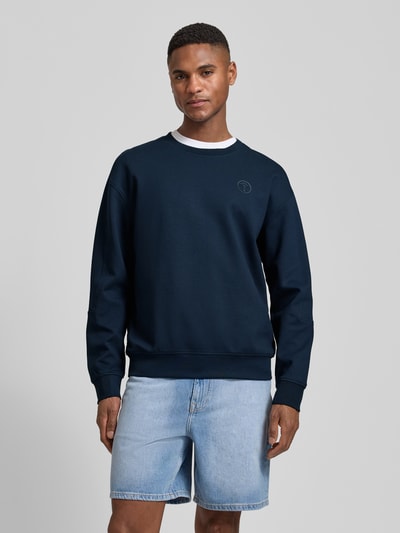 Männermodel trägt Sweatshirt mit Label-Patch Modell 'Juanfrancisco' von JOOP! Collection im Loose Fit, dunkelblau, Ganzkörperansicht von vorne. Baumwoll-Mix mit Stretch-Anteil, sichtbarer Rundhalsausschnitt, glatte Textur, lässiger Stil, Rückenlänge 66 cm, Ärmellänge 62 cm.