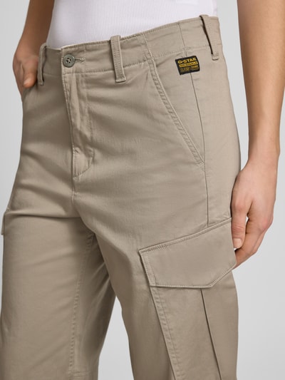 Frauenmodel trägt Loose Fit Cargohose aus Baumwoll-Mix von G-Star Raw in Beige mit mehrfachen Taschen, Nahaufnahme Oberschenkel, Damenmode-Kontext.