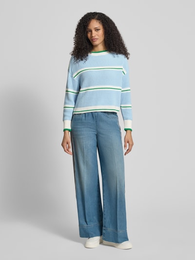 Modelka nosi Strickpullover mit U-Boot-Ausschnitt od Marc Cain, bawełniany miks, krój regular fit, błękitne pasy, przód w pełnej sylwetce.