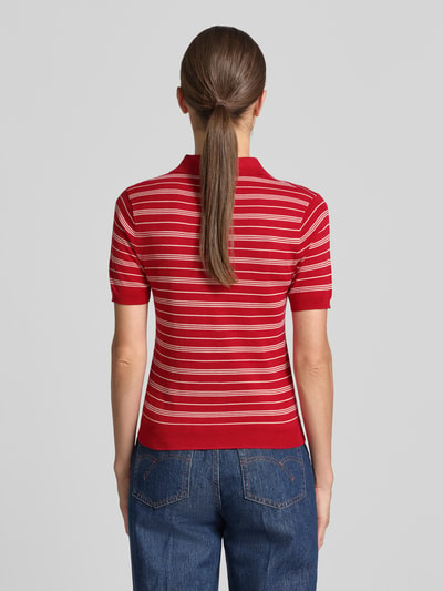 Frauenmodel trägt Slim Fit Strick-Poloshirt aus Viskose-Mix Modell 'POLVITO' von MANGO in Rot mit weißen Streifen, Ganzkörperansicht Rückansicht. Viskose-Baumwoll-Mix, Polokragen, gerippte Abschlüsse, Rückenlänge 53 cm, Ärmellänge 21 cm.