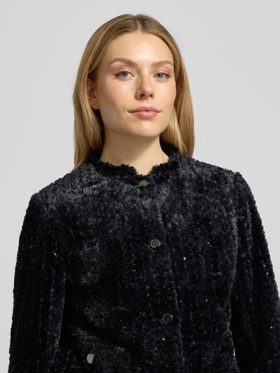 Frauenmodel trägt Slim Fit Blazer mit aufgesetzten Taschen von More & More, Schwarz, Effektgarn, Knopfleiste, Stehkragen, Nahaufnahme Oberkörper. Rückenlänge 54 cm, Brustweite 49 cm, Ärmellänge 63 cm bei Größe 36.
