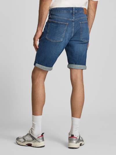 Männermodel trägt Regular Fit Jeansshorts aus Baumwoll-Mix Modell 'RONNIE' von Tommy Jeans, blauer Denim mit Umschlag, 5-Pocket, Ganzkörperansicht Rückansicht.