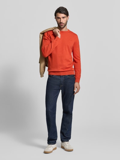 Mannenmodel draagt Regular Fit Pullover aus reiner Baumwolle van s.Oliver RED LABEL in oranje melange, fijngebreid katoen, ronde hals, label stitching, geribde boorden, regular fit; volledige lichaamsaanzicht van voren.