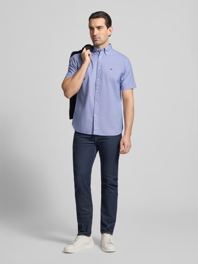 Männermodel trägt Regular Fit Freizeithemd aus reiner Baumwolle von Tommy Hilfiger mit Mini-Hahnentritt Allover-Muster, Ganzkörperansicht von vorne.