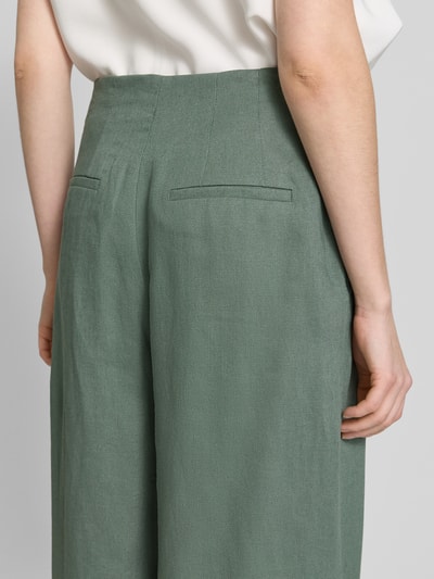 Vrouwenmodel draagt stoffen broek met bandplooien en achterzakken van Jake*s collectie, los model, maat 38 bandwijdte 40 cm, binnenbeenlengte 81 cm, detailopname rug.