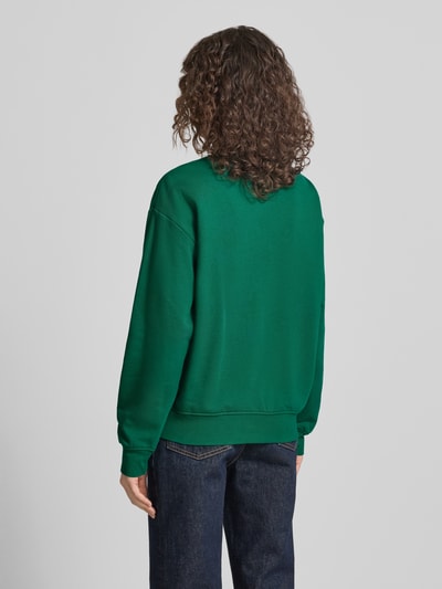 Frauenmodel trägt Sweatshirt mit Label-Print Modell 'GRAPHIC' von Calvin Klein Jeans in Grün; lockere Passform, Baumwoll-Elasthan-Mix, Ganzkörperansicht Rückansicht.