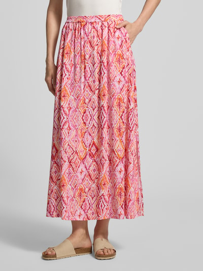 Vrouwenmodel draagt Ausgestellter Maxi-Rock aus reiner Viskose Modell 'EASY JOY' van Vero Moda, all-over grafisch motief, uitlopend, maxi lengte, elastische boord, popeline van zuiver viscose, kleurrijke roze- en oranje tinten, all-over textuur. Ganzkörperaanzicht van voren.