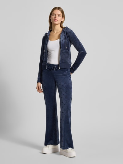 Frauenmodel trägt granatową bluzę rozpinaną z kapturem z mieszanki materiałów z dodatkiem streczu, krój slim fit, model 'MONO MADISON' od Juicy Couture z zamkiem błyskawicznym i kieszenią kangurka; Ganzkörperansicht von vorne.