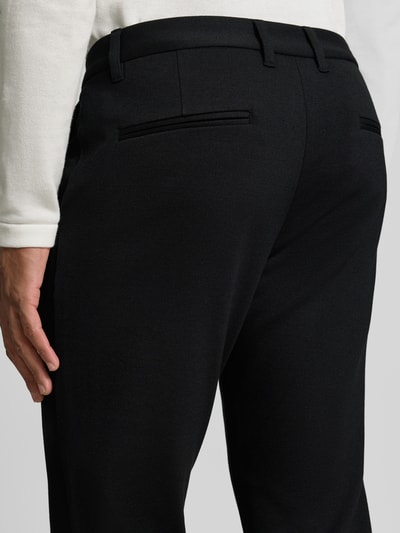 Männermodel trägt Slim Fit Stoffhose mit umgeschlagenen Hosenbeinen von Lindbergh in zwart, elastische materiaalmix met viscose, riemlussen, knoop- en ritssluiting, Bandwijdte maat M: 43 cm, Binnenbeenlengte maat M: 73 cm, detailopname rugaanzicht.
