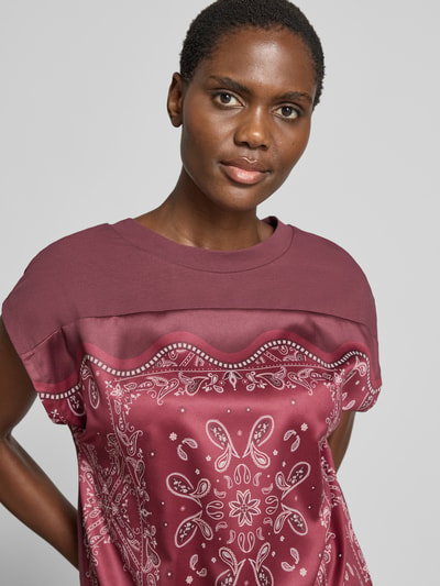 Frauenmodel trägt Blusenshirt mit Knotendetail von Christian Berg Woman Selection aus Satin mit Rundhalsausschnitt, Regular-Fit, Nahaufnahme Oberkörper.