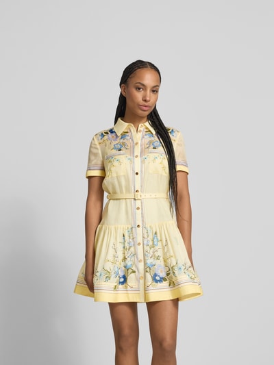 Frauenmodel trägt Minikleid mit Seide-Anteil von Self-Portrait, gelb mit floralen Mustern, tailliert, Brusttaschen, Gürtel, Nahaufnahme Oberkörper.