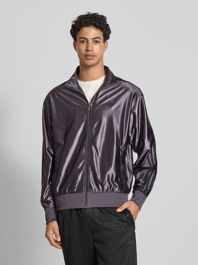 Männermodel trägt Sweatjacke mit Stehkragen von adidas Originals in Dunkelviolett, Reißverschluss, Label-Stitching, Ganzkörperansicht von vorne.