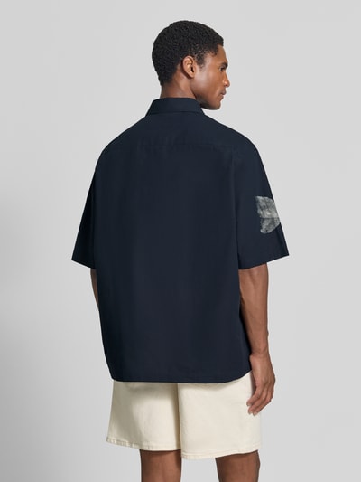 Männermodel trägt Regular Fit Poloshirt aus reiner Baumwolle von Armani Exchange in Dunkelblau mit floralem Design, Rückenansicht.