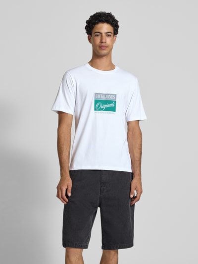 Männermodel trägt T-Shirt mit Statement-Print Modell 'RHYERES' von Jack & Jones aus weißer, gewachster Baumwolle, Regular Fit, Ganzkörperansicht von vorne.