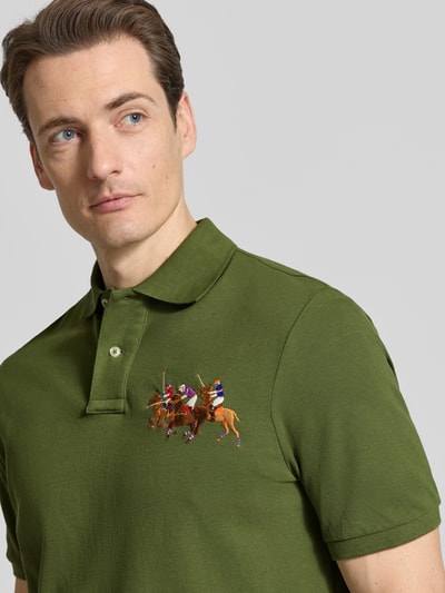 Männermodel trägt Regular Fit Poloshirt aus reiner Baumwolle von Polo Ralph Lauren, efekt: jednolity kolor, krój regular fit, wyhaftowany motyw, kołnierzyk polo, dekolt w serek, krótka listwa guzikowa, krótki rękaw, prążkowane zakończenie rękawów, wykończenie z rozcięciami, asymetryczny krój, pika, czysta bawełna, nahaufnahme górnej części ciała.