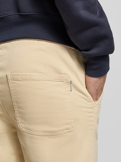 Männermodel trägt Slim Fit Stoffhose mit Eingrifftaschen Modell 'Thunder' von Blend in Beige, Rückansicht Detailaufnahme, elastischer Baumwoll-Mix, Gesäßtasche, legerer Stil.