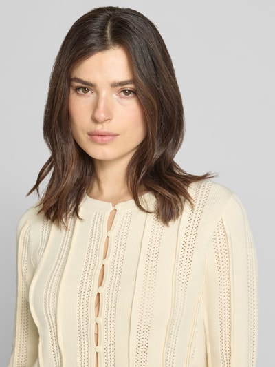 Frauenmodel trägt Strickjacke aus Viskose-Mix von Jake*s Collection in Beige mit Rundhalsausschnitt und Lochstickerei, Nahaufnahme Oberkörper.