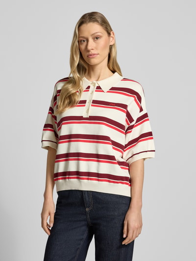 Kobiece modelka ma na sobie koszulkę polo Relaxed Fit Poloshirt aus Viskose-Mix model 'Taia' od Gestuz, czerwone i białe paski, mieszanka wiskozy, krój relaxed fit, kołnierzyk polo, rękaw o dł. 1/2, imitacja dzianiny, elastyczne wykończenia, długość tyłu w rozmiarze S: 58 cm, długość rękawów w rozmiarze S: 22 cm, widok z przodu, ujęcie górnej części ciała.