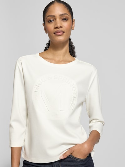 Vrouwenmodel draagt Relaxed Fit Sweatshirt met viscose-aandeel Model 'Emblem' van monari in crème met ronde hals en 7/8-mouw, vooraanzicht bovenlichaam.