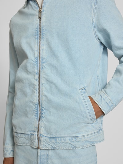 Männermodel trägt Relaxed Fit Jeansjacke aus reiner Baumwolle Modell 'HARRINGTON' von Armedangels in hellblauem Denim mit Umlegekragen und Reißverschluss, seitliche Eingrifftaschen, Nahaufnahme Oberkörper.