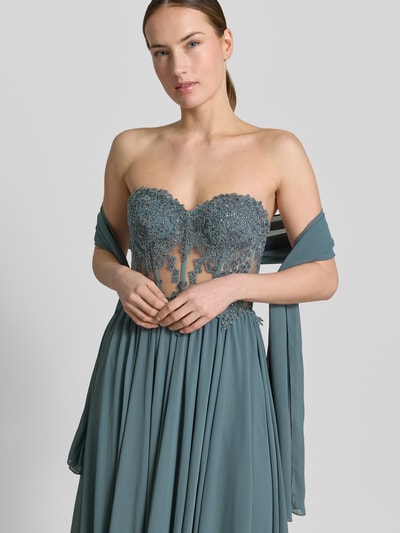 Frauenmodel trägt Abendkleid mit Spitze und Gehschlitz von Mascara in Tailliertem Schnitt, Maxilänge, semitransparenter Spitze, Strasssteinbesatz; Nahaufnahme Oberkörper.