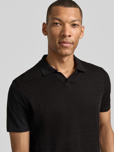 Männermodel trägt Modern Fit Poloshirt mit Polokragen und Label-Detail von MARKUP aus Reine Baumwolle in Schwarz, Nahaufnahme Oberkörper.