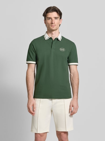 Męski model nosi Regular Fit Poloshirt mit Logo-Print od EA7 Emporio Armani, zielony kolor, bawełniany materiał, widok całej sylwetki z przodu.