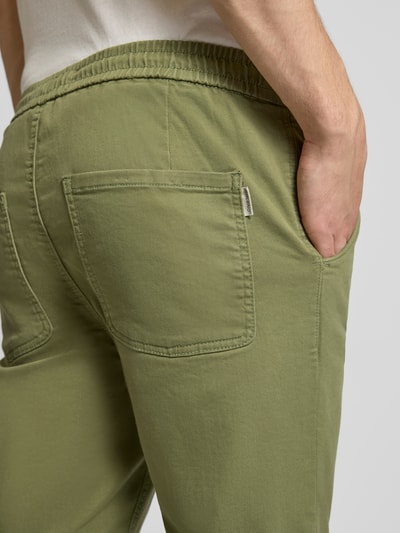 Mężczyzna nosi Slim Fit Stoffhose mit Eingrifftaschen Modell 'Thunder' von Blend, bawełniany elastyczny materiał, kieszenie boczne i tylne, kolor jasnozielony, Szerokość w rozmiarze M: 42 cm, długość wewnętrzna nogawki: 75 cm, detal tylnej części spodni, zbliżenie