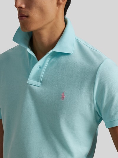 Männermodel trägt Regular Fit Poloshirt aus reiner Baumwolle von Polo Ralph Lauren in Hellblau mit Logo-Detail, Nahaufnahme Oberkörper.