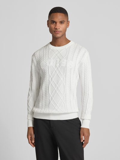 Männermodel trägt weißen Strickpullover aus Baumwoll-Modal-Mix von Guess mit Rautenstruktur, Rundhalsausschnitt, Regular Fit, Nahaufnahme Oberkörper.