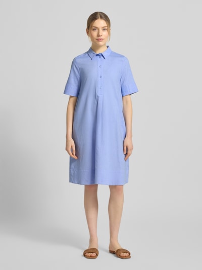 Modelka kobieca nosi knielanges Hemdblusenkleid aus reiner Baumwolle od Milano Italy, luźny fason, kołnierzyk koszulowy, krótkie rękawy, długość do kolan, kolor jasnoniebieski, czysta bawełna, Szerokość w rozmiarze 36: 52 cm, długość pleców w rozmiarze 36: 94 cm, długość rękawa w rozmiarze 36: 28 cm, widok całej sylwetki z przodu.
