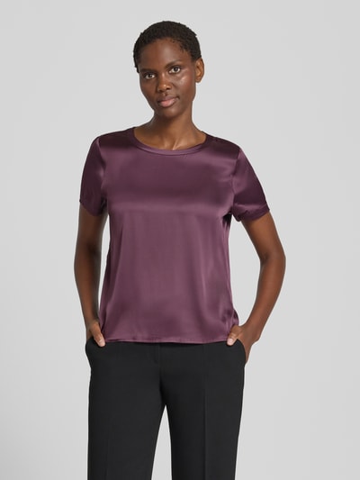 Frauenmodel trägt Blusenshirt aus Satin mit Rundhalsausschnitt von Christian Berg Woman Selection in dunklem Lila, seidig glänzend, glatte Textur, Regular Fit, Kurzarm, Ganzkörperansicht von vorne.