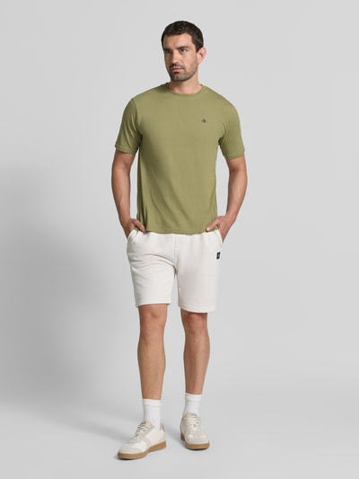 Männermodel trägt T-Shirt mit Label-Stitching und Rundhalsausschnitt von Scotch & Soda in Olivgrün, Reine Baumwolle, Regular Fit, Ganzkörperansicht von vorne.
