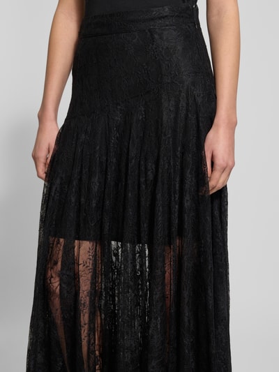 Vrouwenmodel draagt zwarte Copenhagen Muse Spitzenrock in A-lijn Modell 'LEA', maxi lengte, kanten textuur, detailopname taille.
