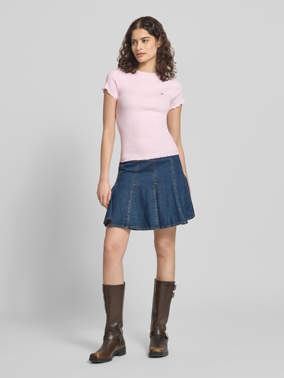 Frauenmodel trägt Slim Fit T-Shirt aus Baumwoll-Mix von Tommy Hilfiger in Rosa mit Logo-Detail, Feinrippstruktur, Kurzarm, Ganzkörperansicht von vorne.